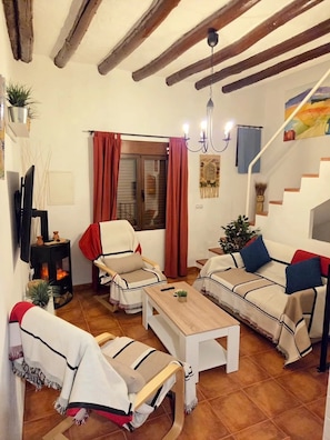 Un salon chaleureux avec une cheminée, un ensemble de canapés, une table basse en bois et un escalier.
