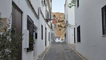 Una estrecha calle empedrada bordeada de edificios blancos con rejas y balcones.