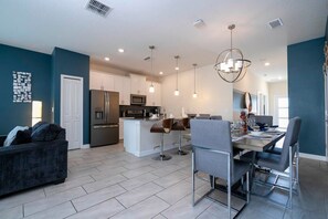 A modern kitchen with a central island, bar stools, and pendant lighting. - Cozy Getaways - Spacious & Ideal Location (Davenport)