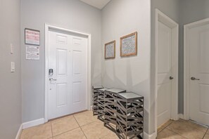 A hallway with a white door, two framed pictures on the wall, and a stack of metal crates. - Cozy Home Near Disney Parks - Prime Location (Kissimmee)