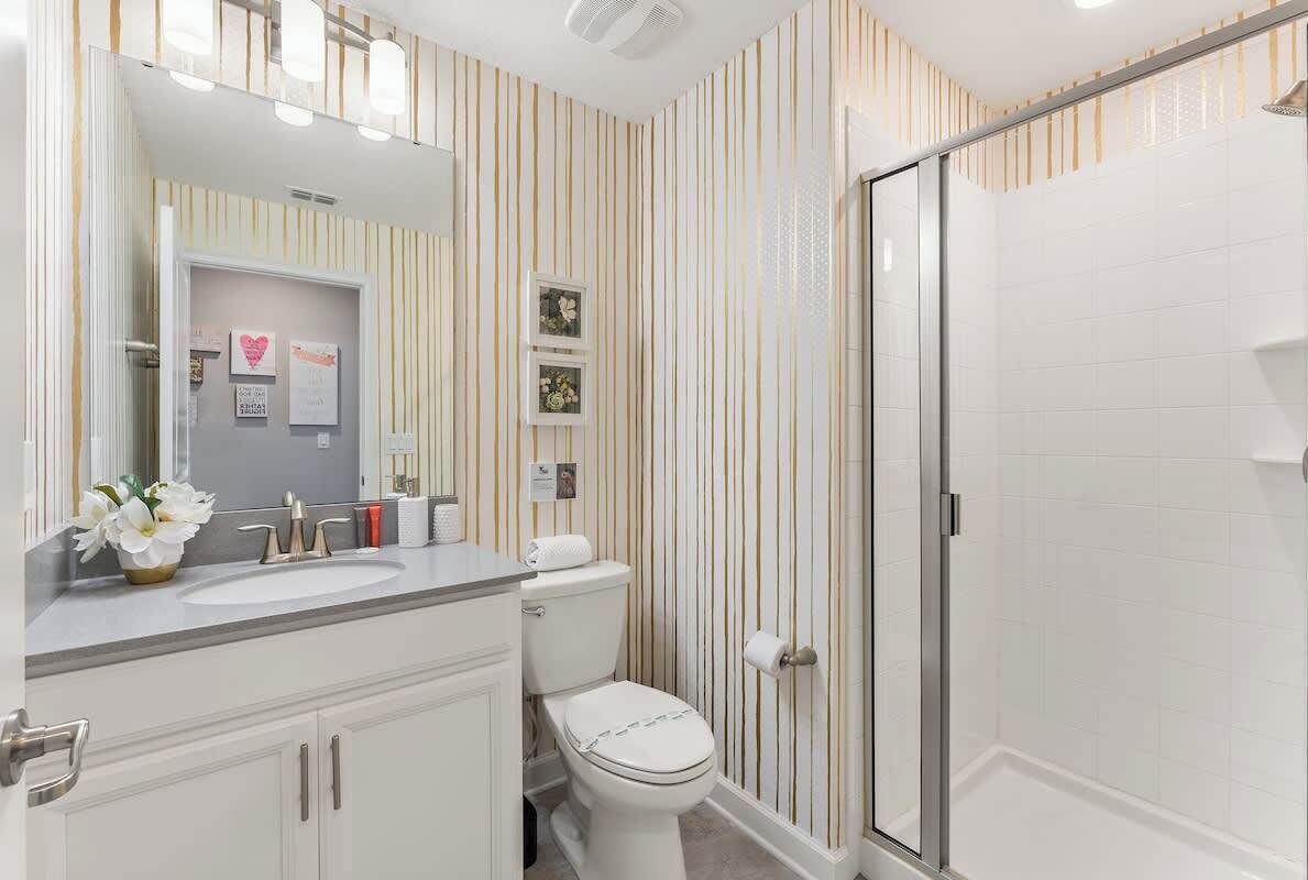 A bathroom with a shower, a toilet, a sink, and a mirror.