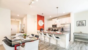 A modern kitchen with white cabinets, stainless steel appliances, and a red accent wall. - Cozy Home in Amazing Resort for Perfect Vacations (Davenport)