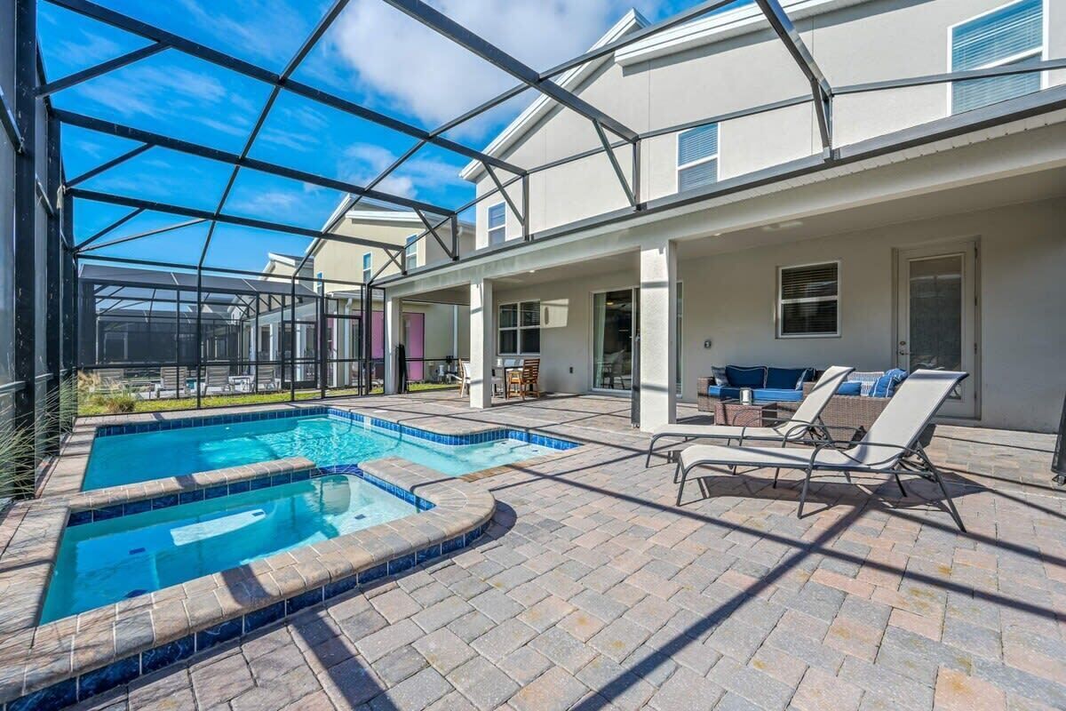 Una piscina exterior cubierta con sillas de descanso, una zona de patio y vistas del vecindario.