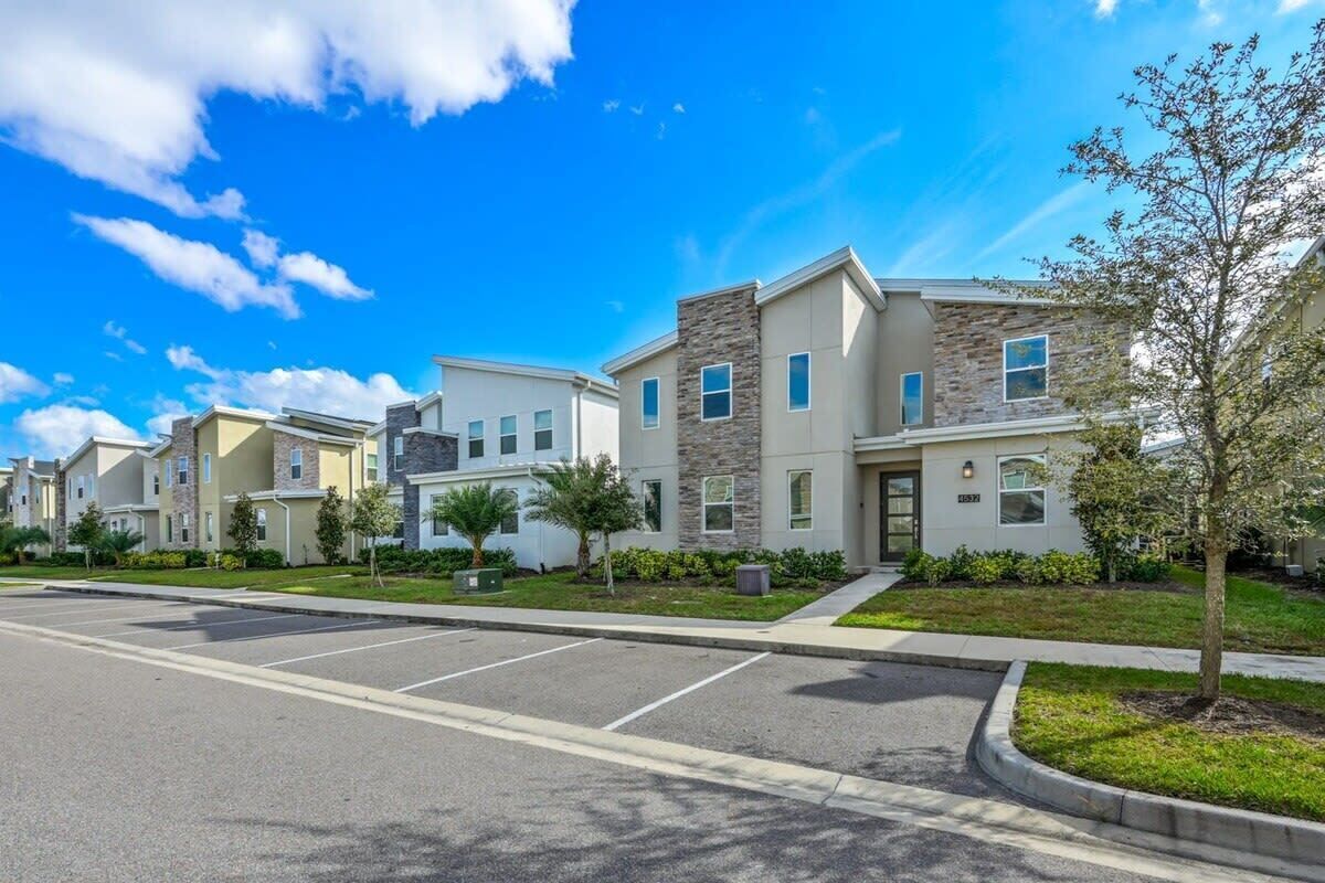 A row of modern townhouses with a parking lot in front.
