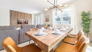 Un comedor con una mesa de madera dispuesta para cuatro personas, rodeada de sillas de cuero.