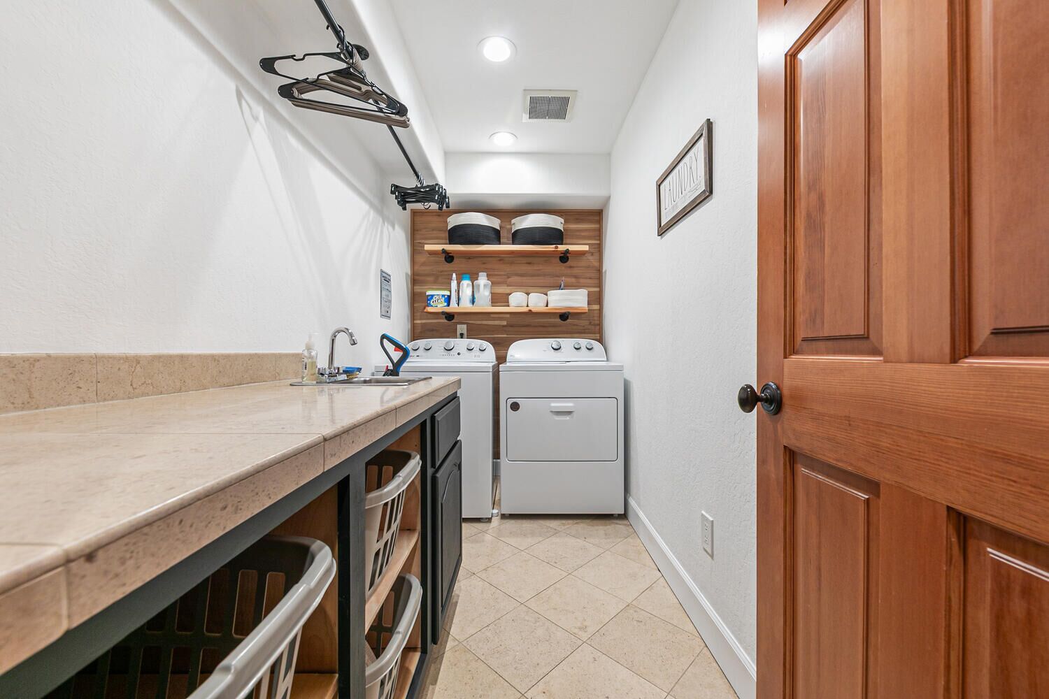 A laundry room with a washing machine, dryer, and shelves with laundry supplies.