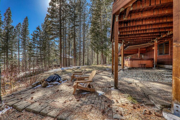Une cabane en bois dotée d’un espace extérieur abrité, entourée de grands pins.