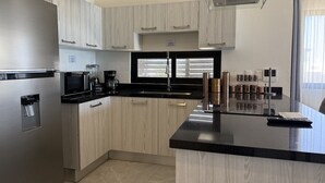 A modern kitchen with a stainless steel refrigerator, a black countertop, and light wood cabinetry. - Oceanview Condo in Palos Prietos | Pool + 1 Block to Beach (Mazatlán)