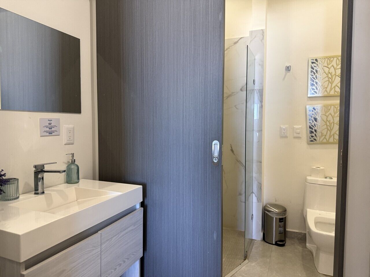A bathroom with a white sink, a mirror, a shower, and a toilet.