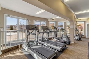 Une salle de sport équipée de tapis de course, d’une horloge et offrant une vue sur l’extérieur.