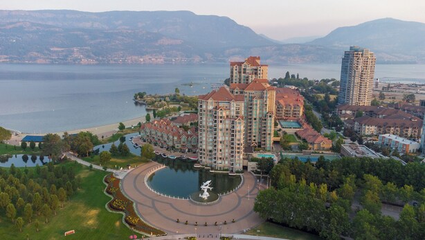 Un hôtel de grande hauteur doté de nombreux balcons, d’une cour intérieure avec une fontaine et offrant une vue sur un lac.