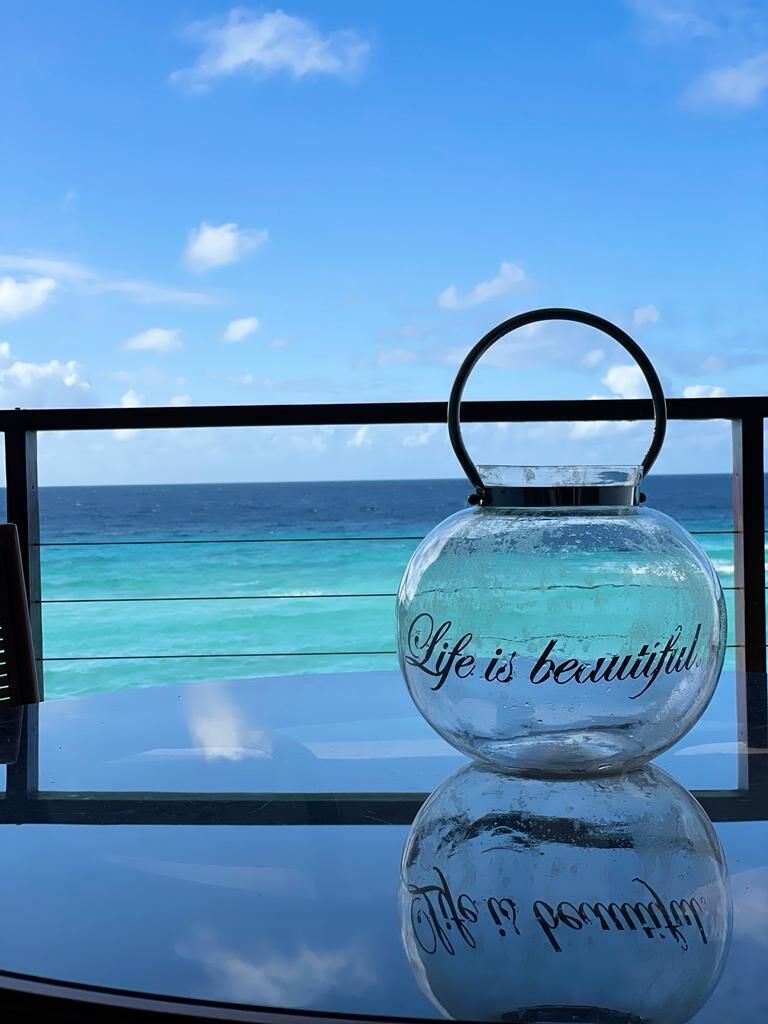 A clear view of the ocean through a window, with a decorative glass object on the table.