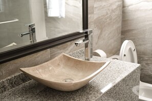 A bathroom with a marble sink, a mirror, and a toilet. - Hotel Asís (San Juan de los Lagos)