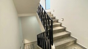 A staircase with a geometric patterned floor, a black railing, and a window at the top. - Hotel Asís (San Juan de los Lagos)