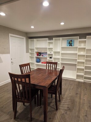A dining area with a wooden table and chairs, surrounded by white shelving units with books and decorative items. - Large brick home centrally located in Limestone. (Limestone)