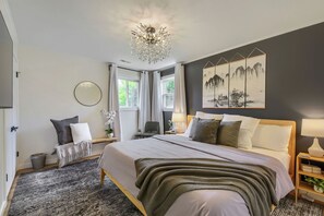 Ein Schlafzimmer mit einem großen Bett, einer Kristallleuchter, einem Gemälde und Blick ins Freie.