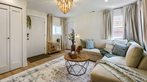 A well-lit living room with a sofa, a coffee table, and a chandelier. - Inviting & Serene: A Book Lover’s Haven (Homewood)