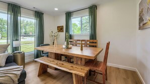 A dining area with a wooden table, chairs, a bench, and a vase with flowers. - Inviting & Serene: A Book Lover’s Haven (Homewood)