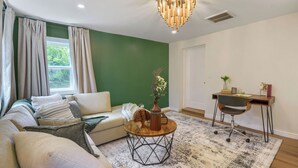 A living room with a sofa, coffee table, and a desk with a chair. - Inviting & Serene: A Book Lover’s Haven (Homewood)