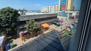A view of a cityscape with a building featuring a colorful mural, a restaurant with outdoor seating, and a clear sky. - Apartment EST (Rimouski)