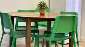 A dining table with four green chairs, a potted plant on the table, and a refrigerator in the background. - Apartment EST (Rimouski)