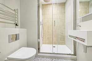 Une salle de bain moderne avec une douche à parois de verre, des toilettes blanches et un meuble-lavabo avec un miroir.