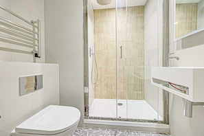 Une salle de bain moderne avec une douche à parois de verre, des toilettes blanches et un meuble-lavabo avec un miroir.