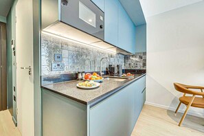 Une cuisine moderne dotée d’un îlot central, d’appareils électroménagers en acier inoxydable et d’un mur d’accent bleu.