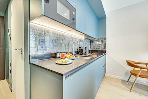 Une cuisine moderne dotée d’un îlot central, d’appareils électroménagers en acier inoxydable et d’un mur d’accent bleu.