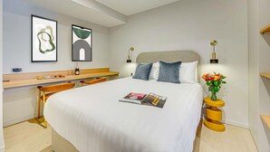 Una habitación de hotel moderna con cama, mesita de noche y escritorio.