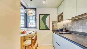 Una cocina moderna con comedor, una ventana y una obra de arte abstracta enmarcada.