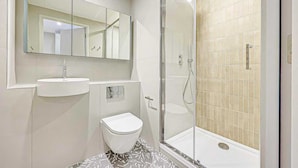Et moderne badeværelse med toilet, vask og bruser.