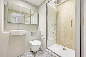 Ein modernes Badezimmer mit Toilette, Waschbecken und Dusche.