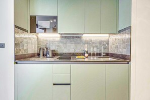 Eine moderne Küche mit Einbau-Mikrowelle, Wasserkocher, einer Weinflasche und Gläsern auf der Arbeitsfläche.