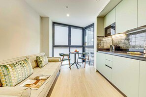 Eine moderne Wohnung mit Sofa, Esstisch, Stühlen und einer Küchenzeile.