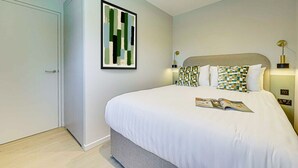A bedroom with a bed, a framed abstract painting, bedside lamps, and a magazine on the bed. - Two-Bedroom Apartment at Farringdon by Dmontrio (London)
