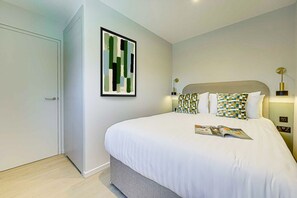 A bedroom with a bed, a framed abstract painting, bedside lamps, and a magazine on the bed. - Two-Bedroom Apartment at Farringdon by Dmontrio (London)