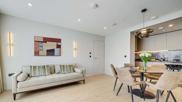 A modern living room with a sofa, dining table, chairs, and a kitchen area. - Two-Bedroom Apartment at Farringdon by Dmontrio (London)