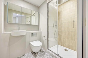 Ein modernes Badezimmer mit Toilette, Waschbecken und Dusche.