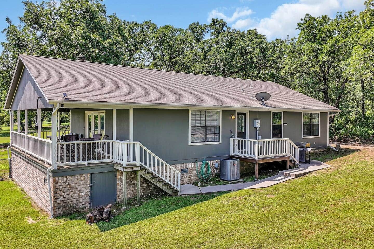 A two-story house with a covered porch, a satellite dish, and a small outdoor grill area.