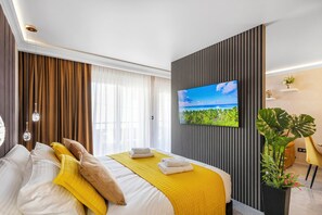 Et moderne hotelværelse med en stor seng, et fladskærms-tv, en potteplante og udsigt til det fri.
