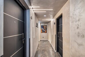 Ein Flur mit modernem Design, der ein Gemälde an der Wand, eine Tür rechts und eine Deckenleuchte zeigt.