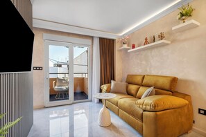 Ein modernes Wohnzimmer mit einer Couch, einem kleinen runden Tisch und einer Schiebetür zu einem Außenbereich.