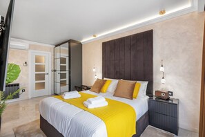 Una habitación de hotel moderna con una cama grande, mesitas de noche, un armario y un espejo.