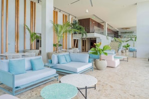 Eine geräumige Lobby mit einem hellblauen Sofa, einem runden Tisch und Topfpflanzen.