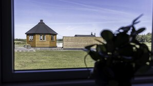Une petite maison en bois avec un toit conique, une cour herbeuse et une clôture en bois.