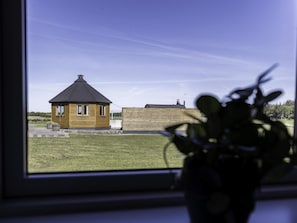 A small wooden house with a conical roof, a grassy yard, and a wooden fence. - 4 Star Holiday Home in Aabybro (Aabybro)