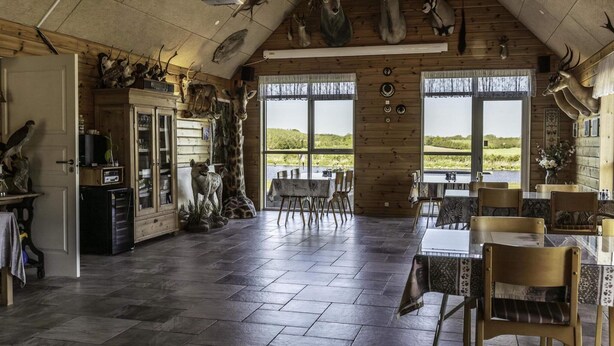 Une pièce spacieuse avec un plafond haut, des murs en bois et une grande fenêtre donnant sur l’extérieur.