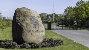 Une grande pierre sur laquelle est gravée une image de cerf, et sur laquelle on peut lire le mot « Kragelund », à l’entrée d’un parc.