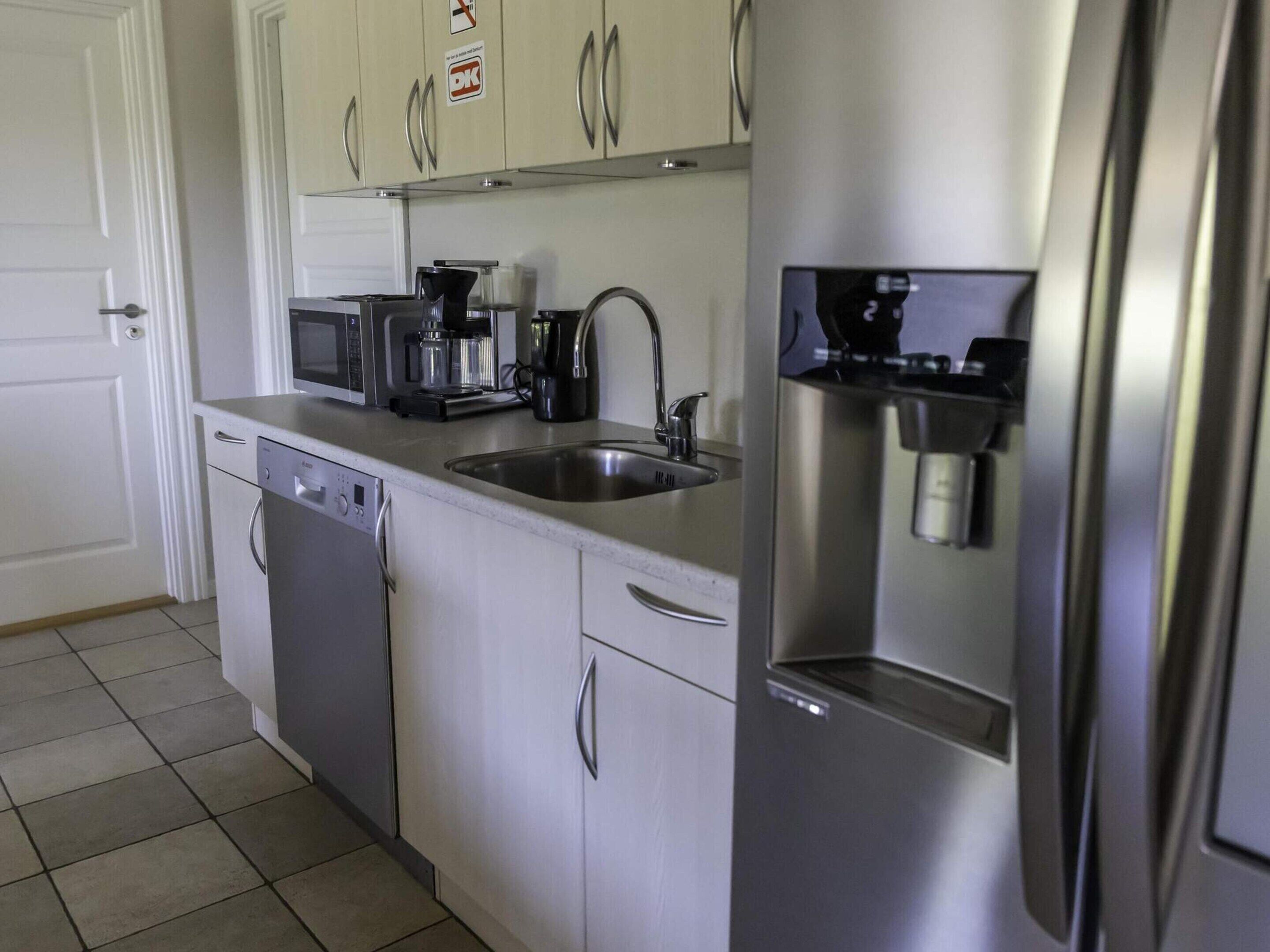 A kitchen with a dishwasher, microwave, coffee maker, and a refrigerator.
